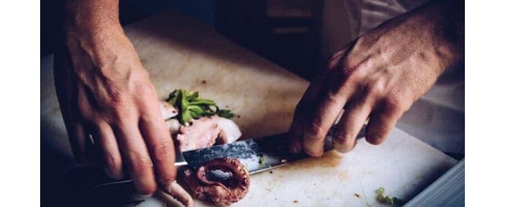 Chef using chef knife to cut squid tentacle