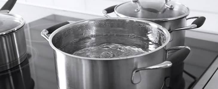 Metal pans with boiling water in kitchen